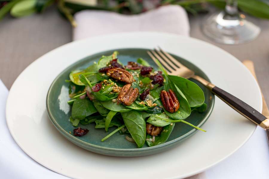 Candied pecan nuts with cranberries on a bed of spinach leaves with a toasted sesame dressing